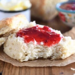 Half of a biscuit with butter and jam.