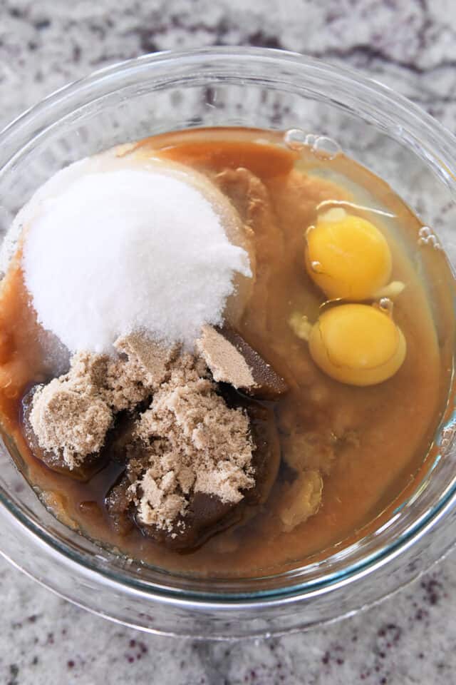 Glass bowl with eggs, white sugar, brown sugar, applesauce, and oil