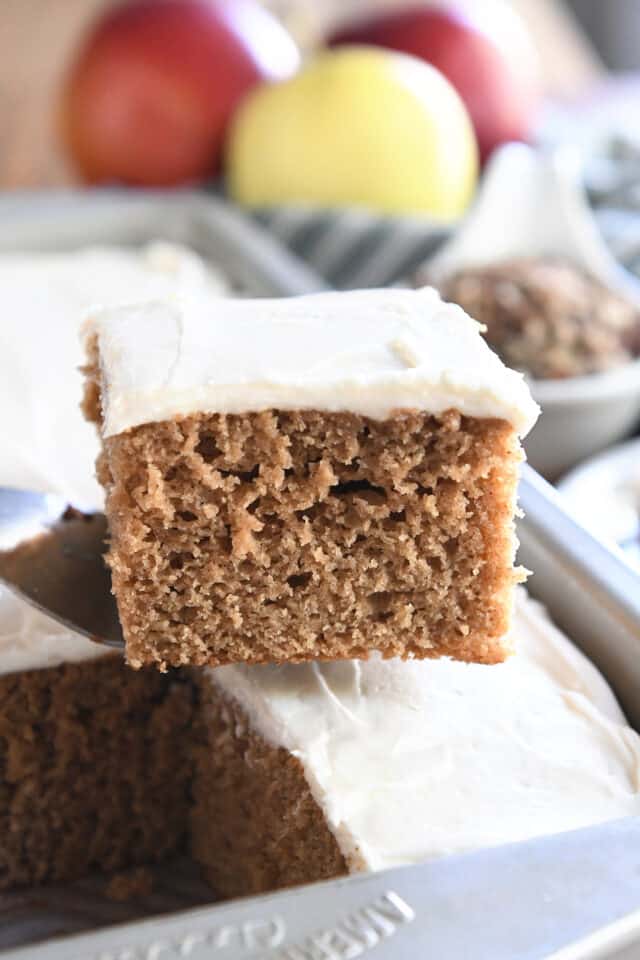Square of frosted applesauce spice cake on spatula.