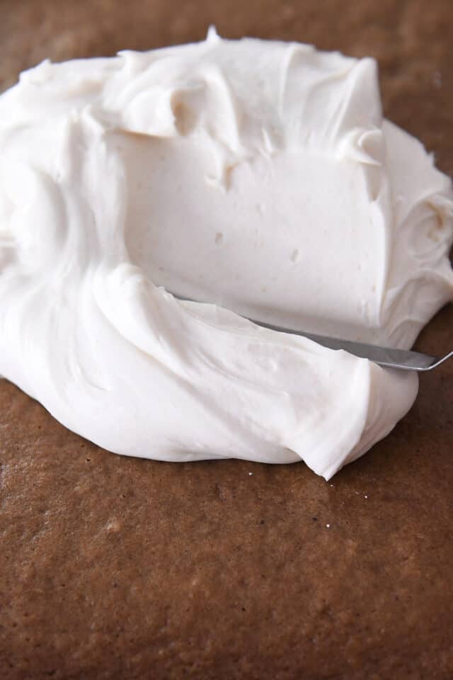 Spreading cream cheese frosting on top of applesauce spice cake.