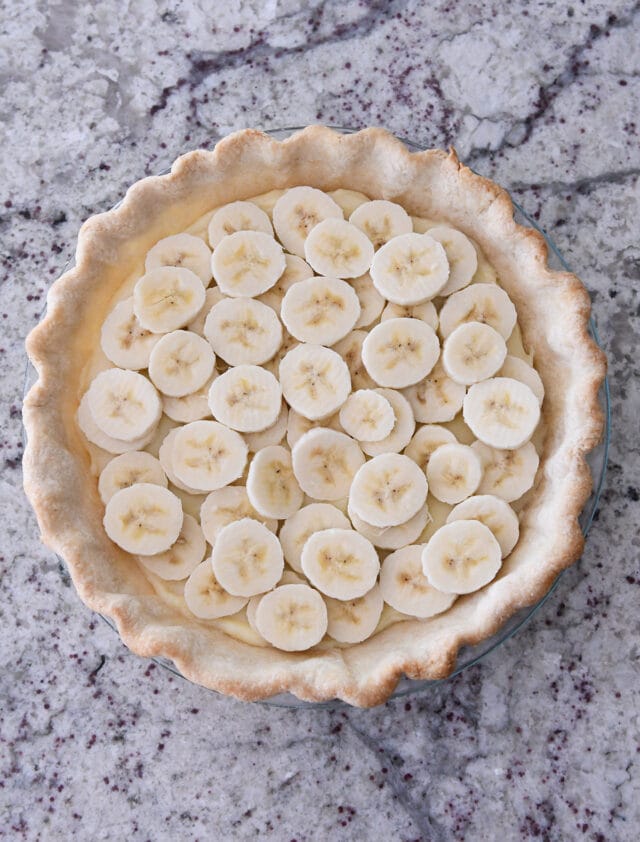 Sliced bananas layered on top of vanilla custard in baked pie shell.