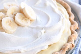 Whole banana cream pie topped with sliced bananas and whipped cream.