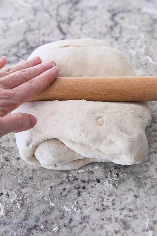 Rolling out tri-folded dough with rolling pin.