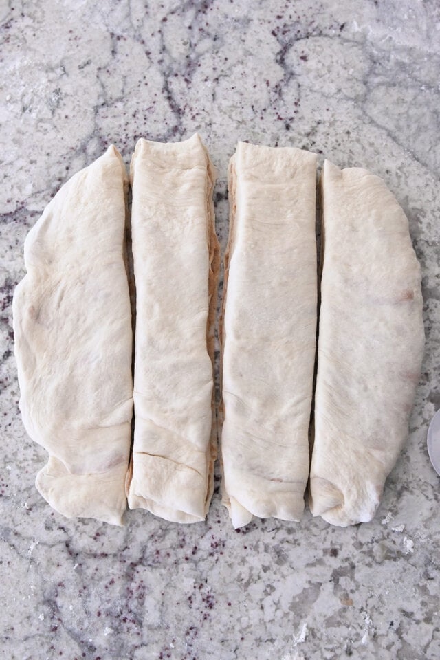 Square of dough cut into four strips for croissant bread with cinnamon sugar filling.