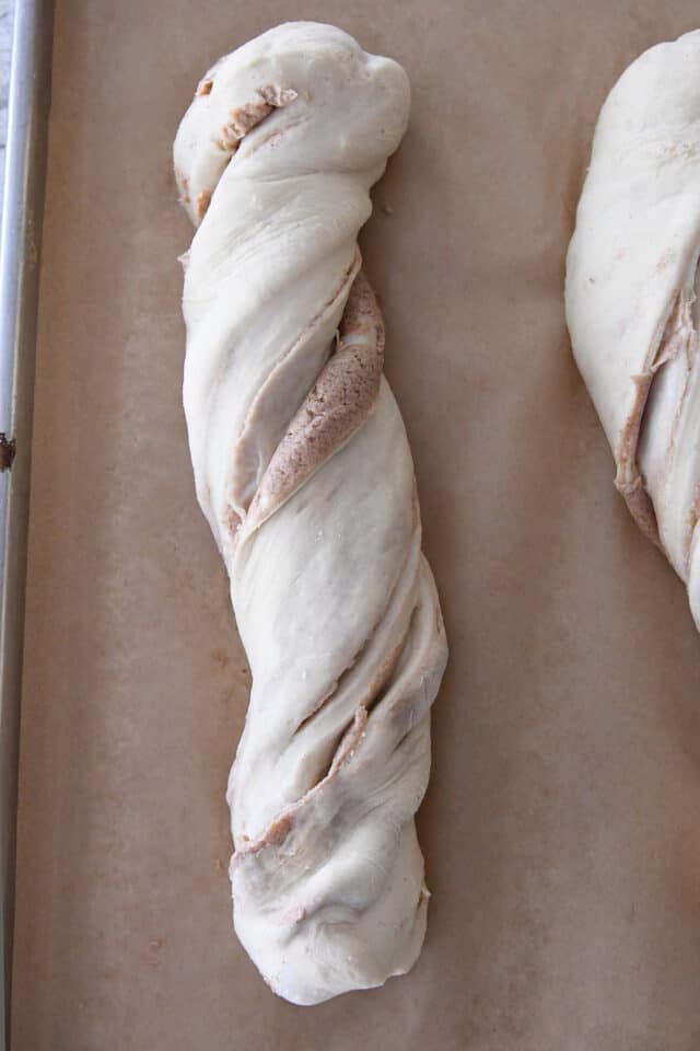 Unbaked loaf of croissant bread on brown parchment paper.