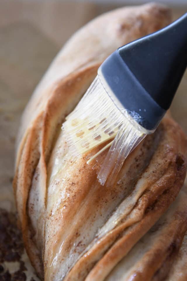 Brushing butter on baked twisted croissant bread.