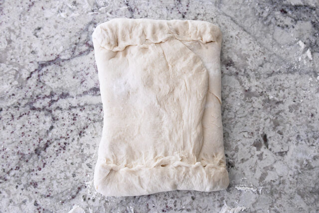 Butter packet folded into dough with dough edges pinched and sealed.