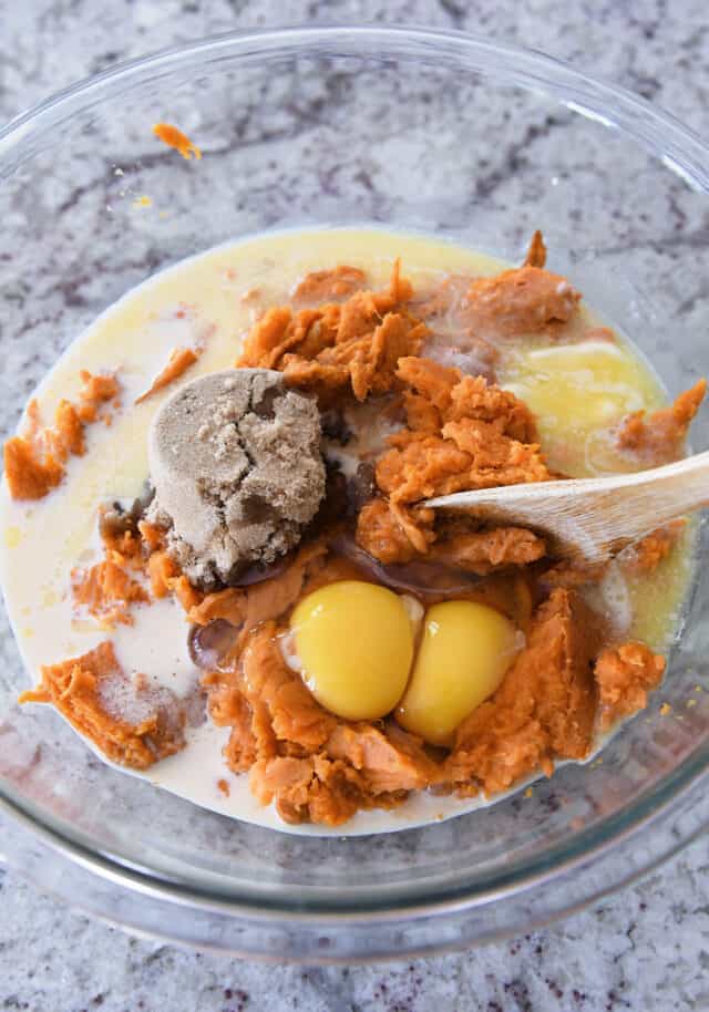 Glass bowl with mashed sweet potatoes, eggs, brown sugar, milk, and salt.