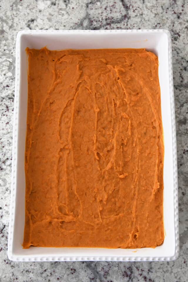 White baking dish with sweet potato filling spread evenly.