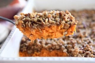 Serving spoon with sweet potato casserole and pecan topping.