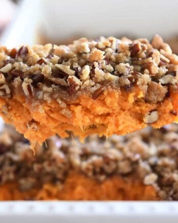 Serving spoon with sweet potato casserole and pecan topping.