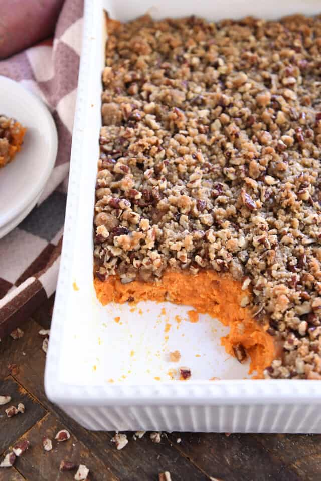 Scoop taken out of sweet potato casserole in white baking dish.