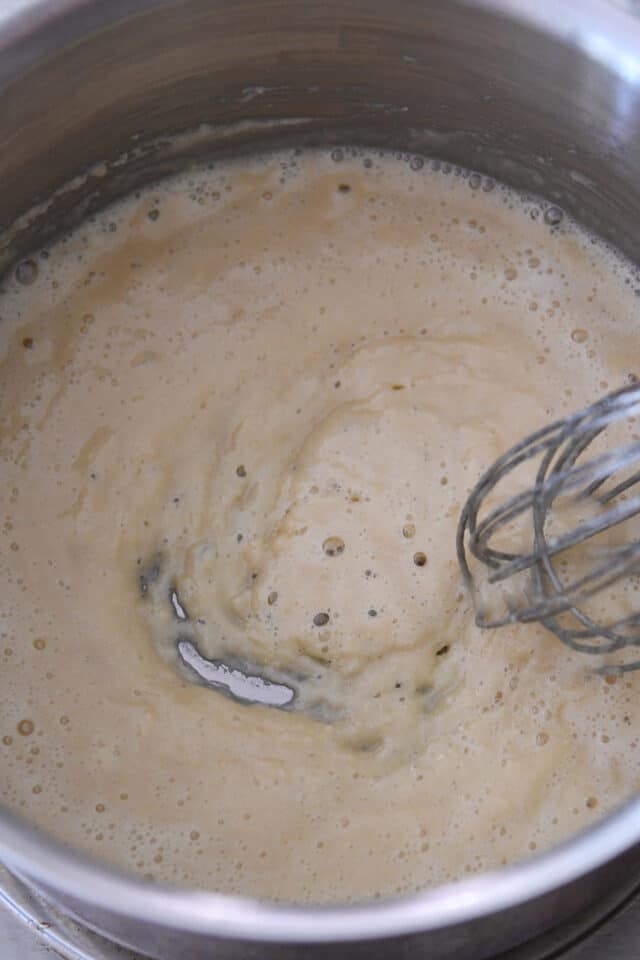 Cooking roux in saucepan with whisk.