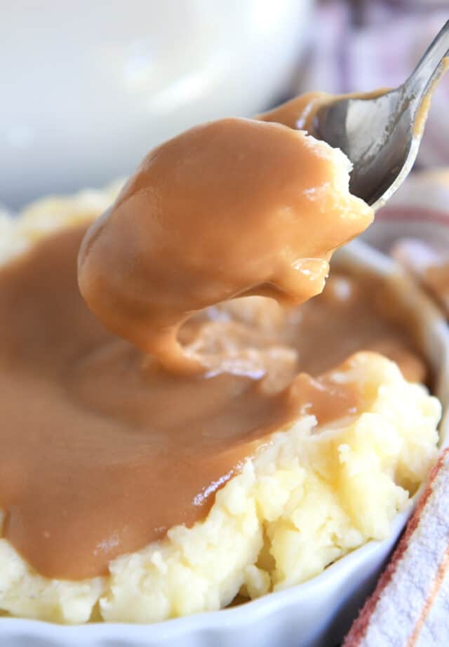 Spoon lifting up mashed potatoes and gravy.