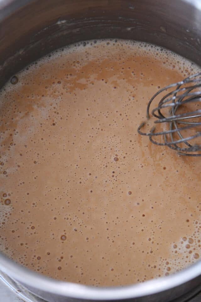 Cooking roux for gravy in pan with whisk.