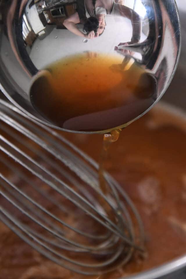 Adding hot broth to pan of gravy.