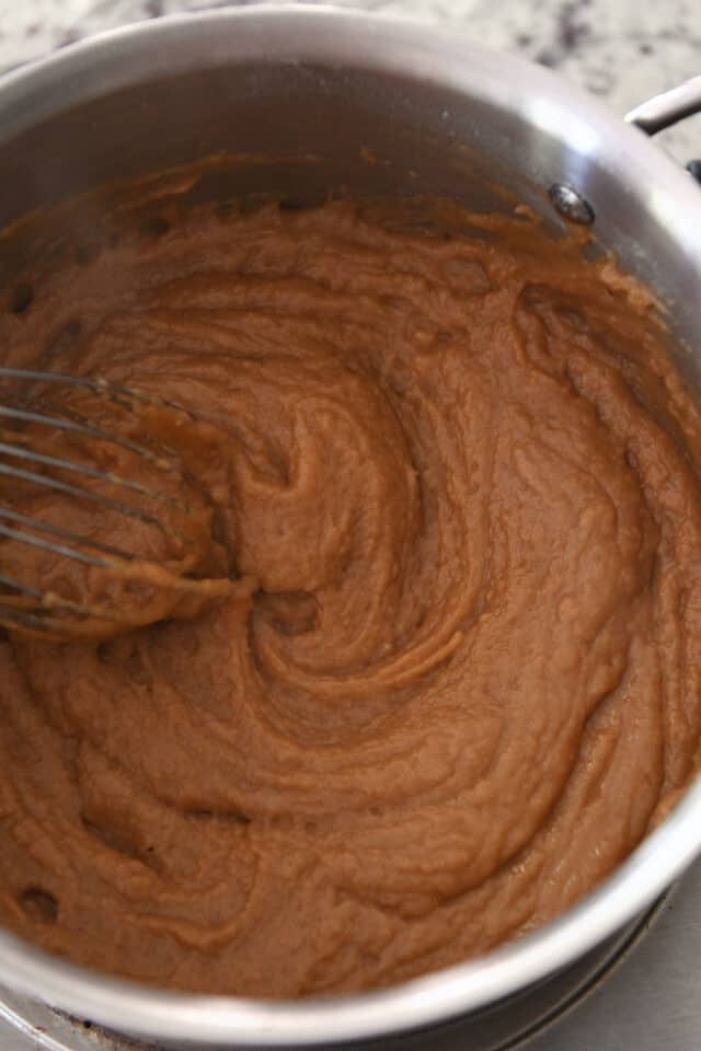 Whisking roux and broth for gravy in saucepan.