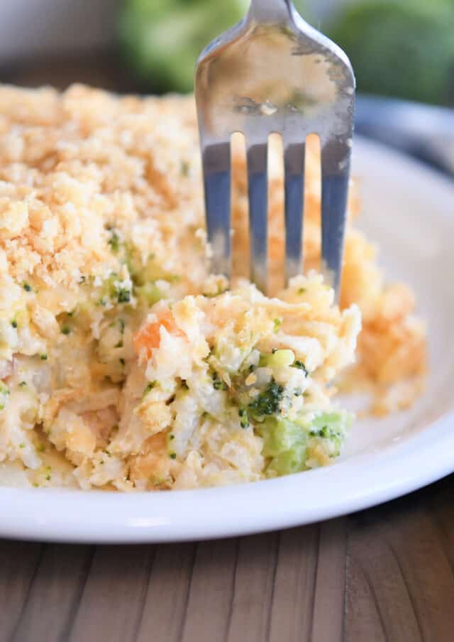 Fork taking bite of casserole with rice, broccoli and carrots.