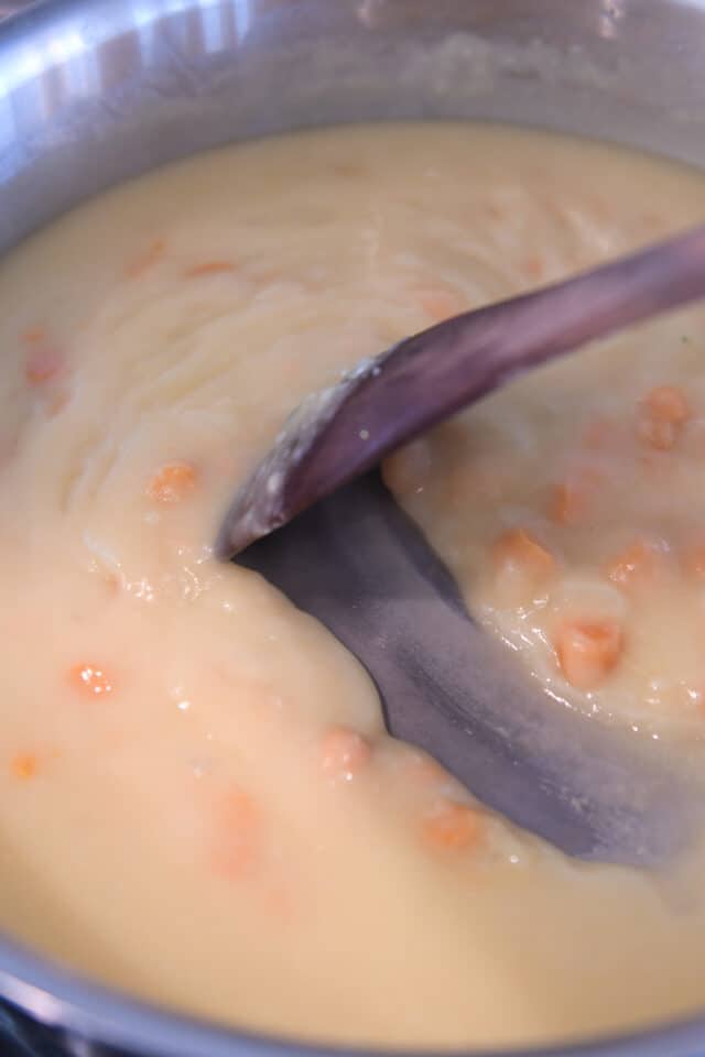 Thick cream sauce in skillet with carrots.