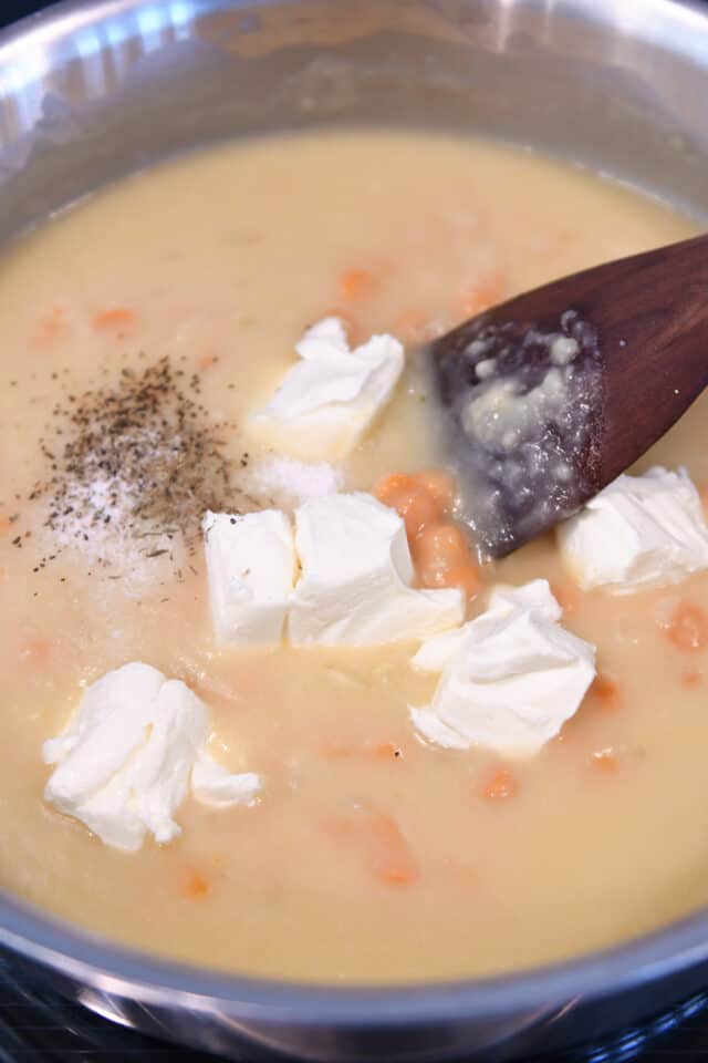 Adding cream cheese, salt and pepper to cream sauce in skillet with carrots.