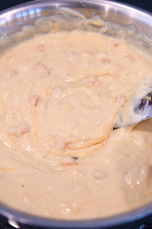 Stirring cheese sauce with wooden spoon.