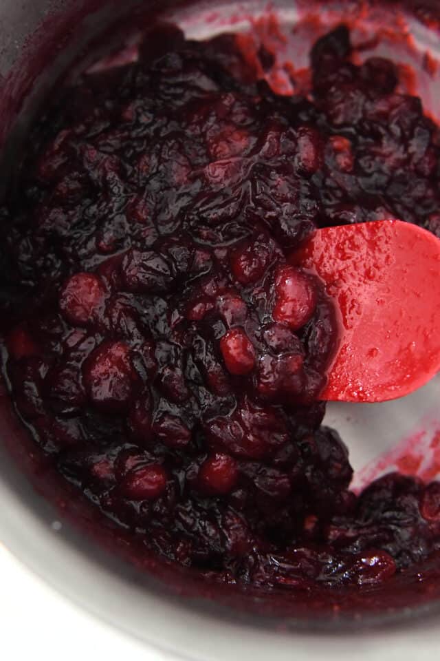 Quick cranberry jam in saucepan with rubber spatula.