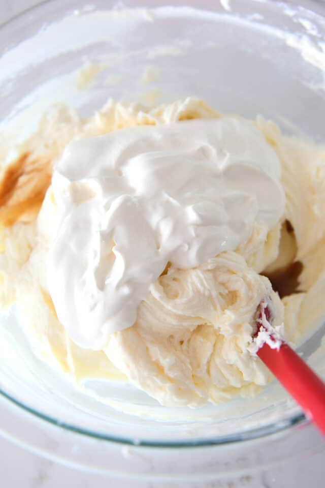 Cheesecake batter and sour cream in glass bowl.