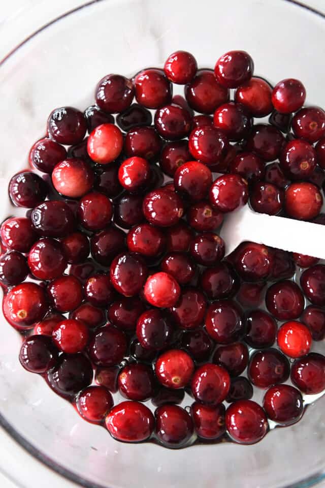 Glass bowl with simple syrup and fresh cranberries.