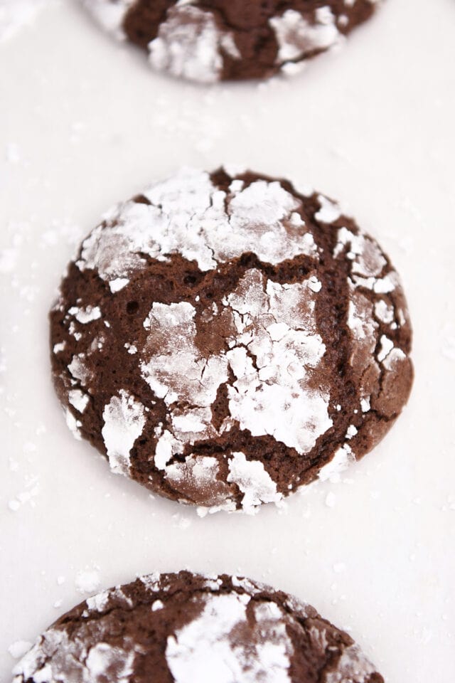 Chocolate crinkle cookie on parchment paper.