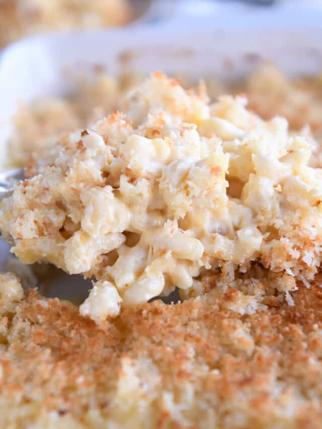 Scooping helping of baked macaroni and cheese with metal spoon.