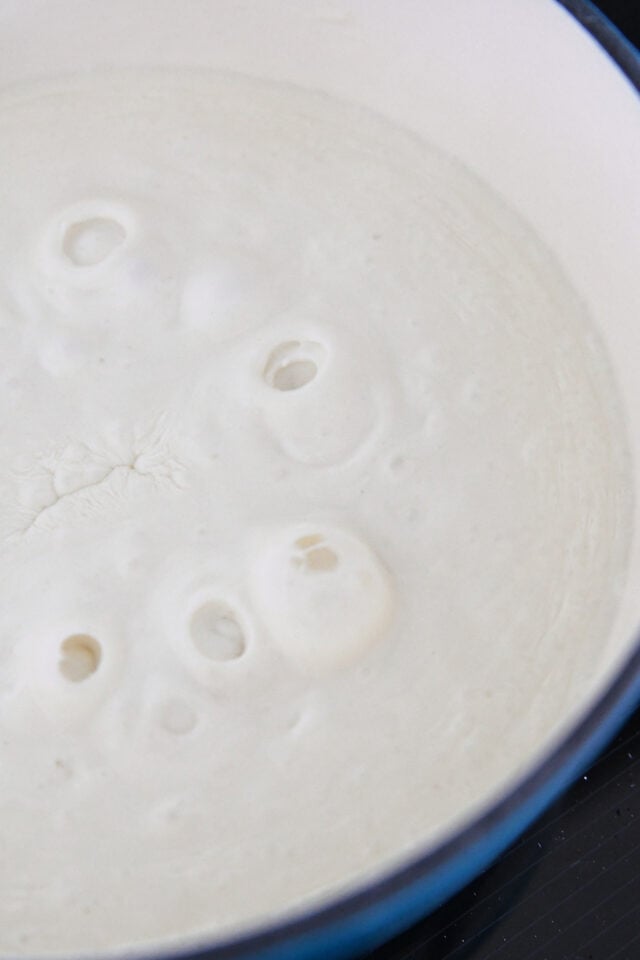 White sauce bubbling in blue pot.