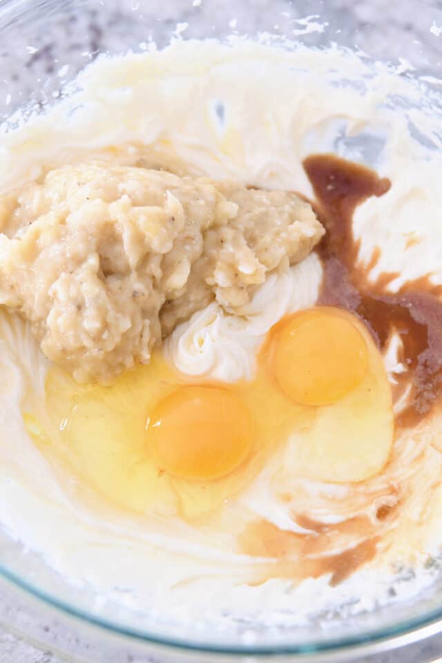 Eggs, mashed bananas, and vanilla in bowl with banana bread batter.