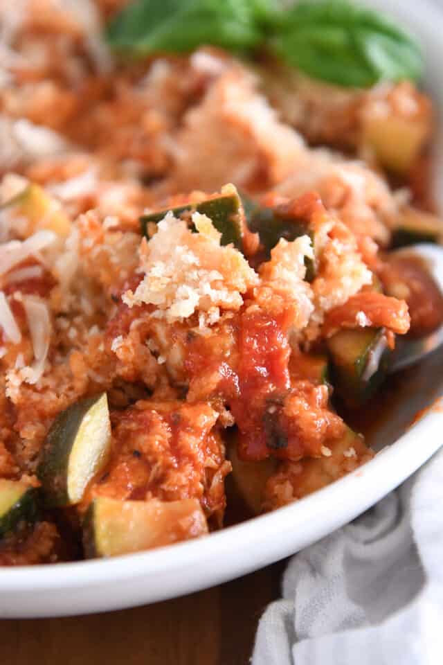 Zucchini, panko bread crumbs, tomato sauce and chicken in white bowl.