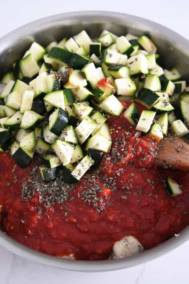 Skillet with crushed tomatoes, chicken, herbs and zucchini.