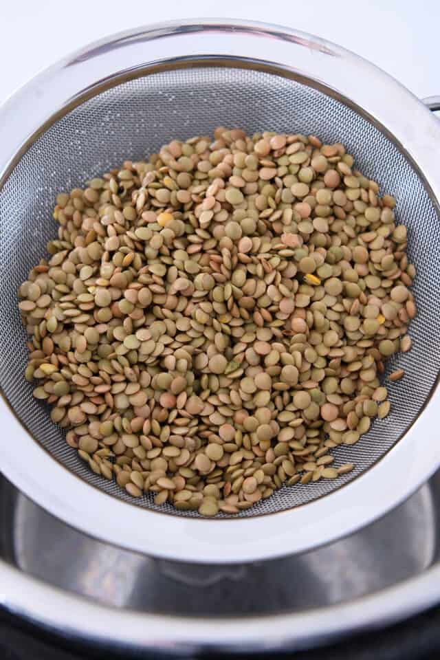 Washed and rinsed brown and green lentils in strainer.