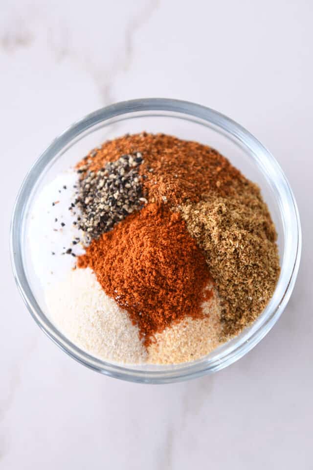 Small glass bowl with paprika, chili powder, cumin, pepper, salt, onion powder and garlic powder.
