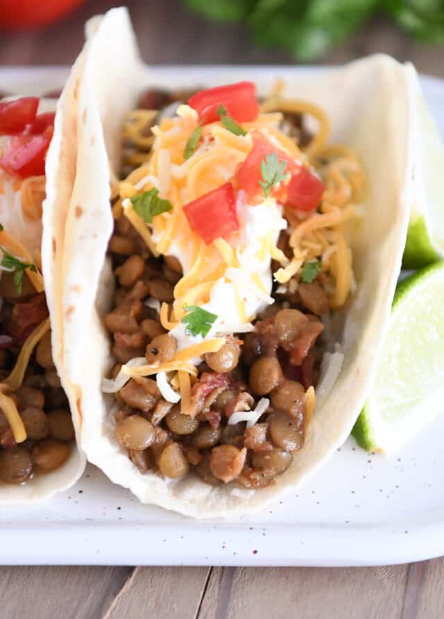 Cooked lentils with seasonings in flour tortilla with sour cream, cheese, and tomatoes.