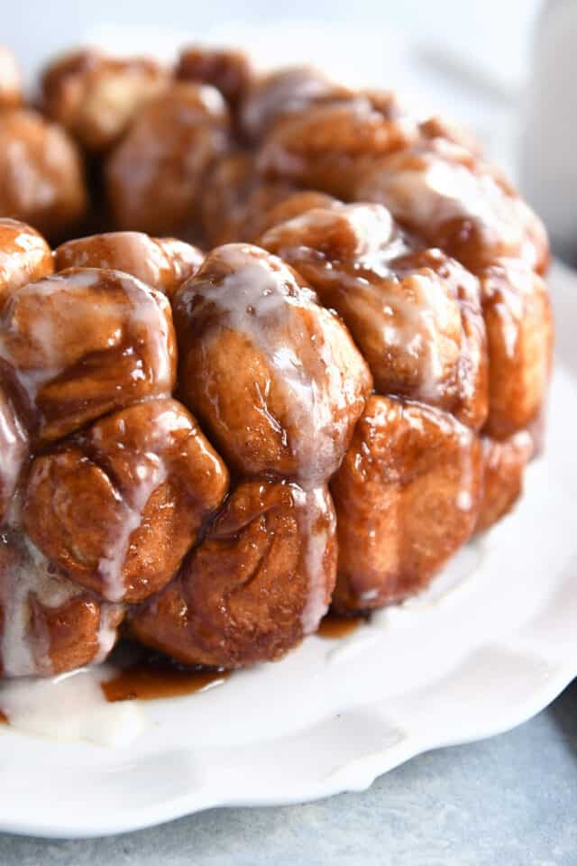 Pull apart monkey bread with glaze on white tray.