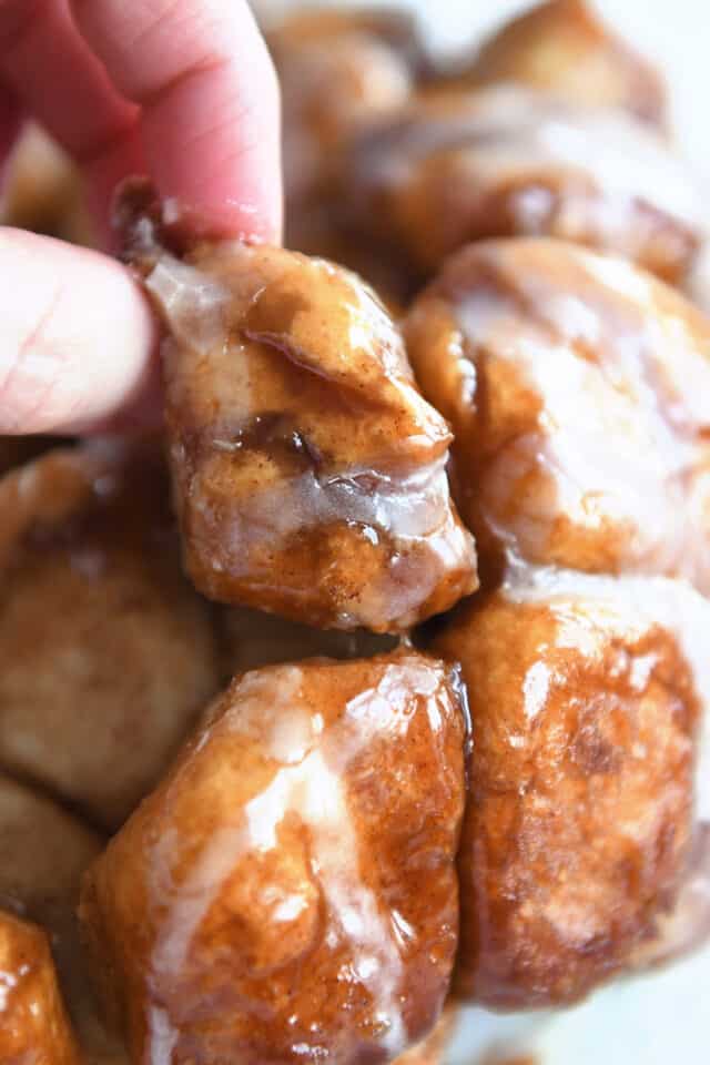 Picking up piece of monkey bread from baked pile of monkey bread pieces.