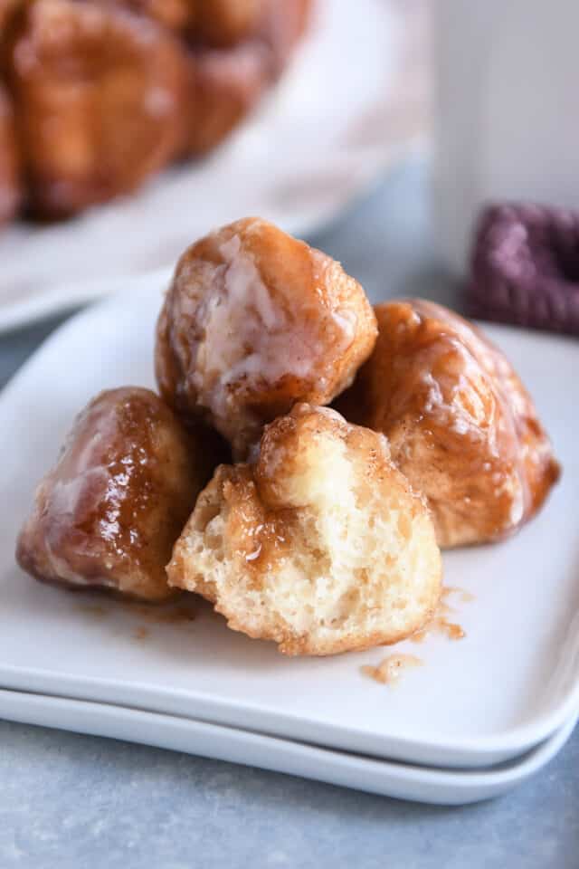 Four pieces of baked monkey bread on white plate with one piece cut in half.