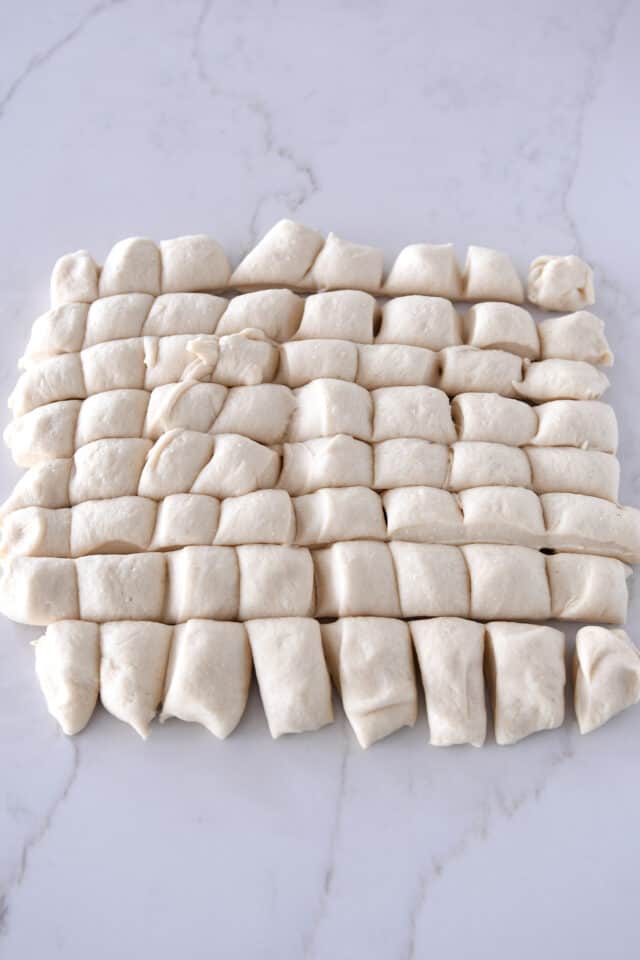 Sheet of dough on counter cut into 64 pieces.