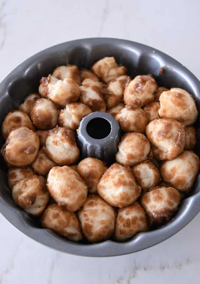 Risen balls of cinnamon and sugar dough in bundt pan.