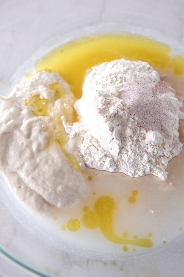 Sourdough starter, flour, salt, oil and water in glass bowl.