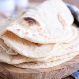 Folded piece of sourdough flatbread on stack of other flatbread.