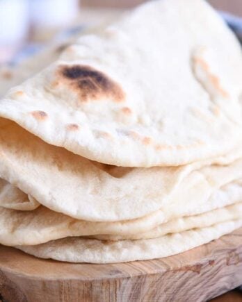 Folded piece of sourdough flatbread on stack of other flatbread.