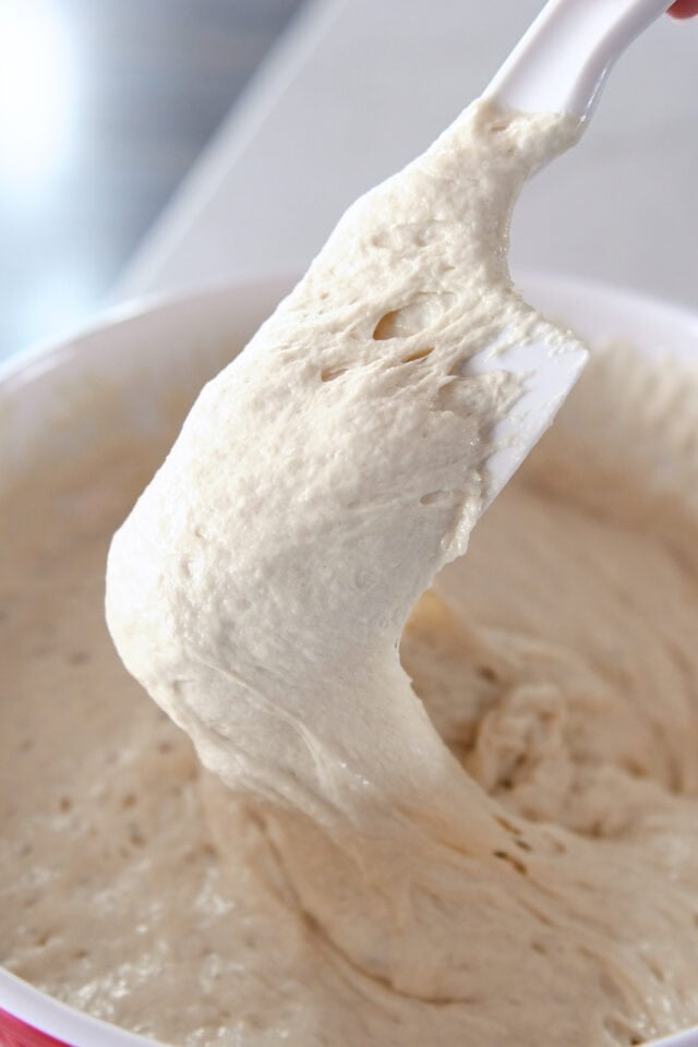 Rubber spatula stirring sourdough starter.