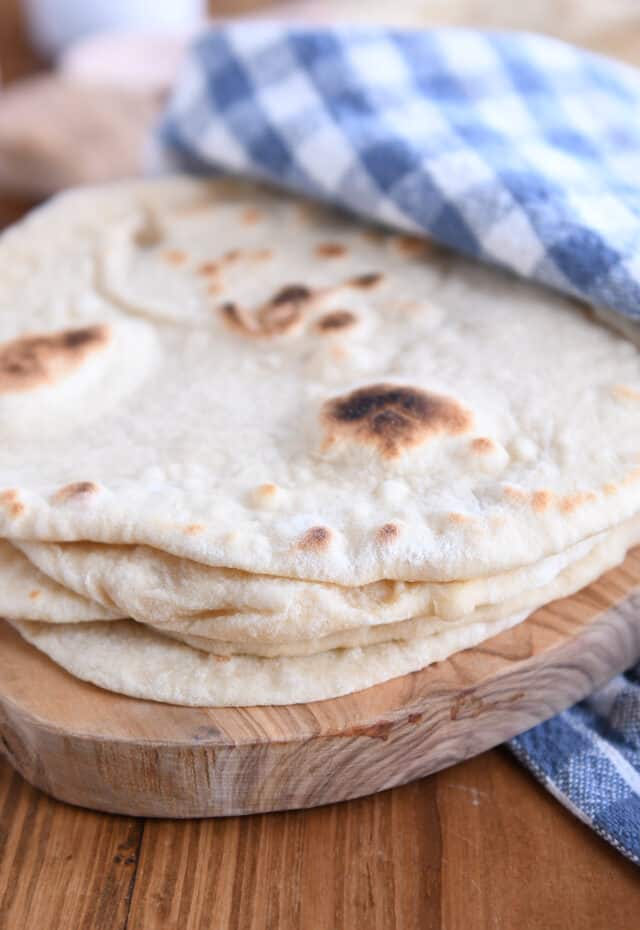 Stack of four sourdough flatbreads on wood cutting board.