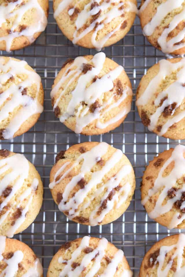 Twelve glazed cinnamon roll muffins on cooling rack.