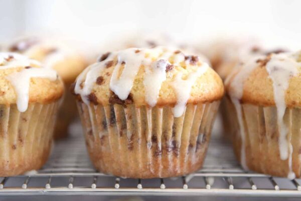 Glazed cinnamon roll muffin on cooling rack.