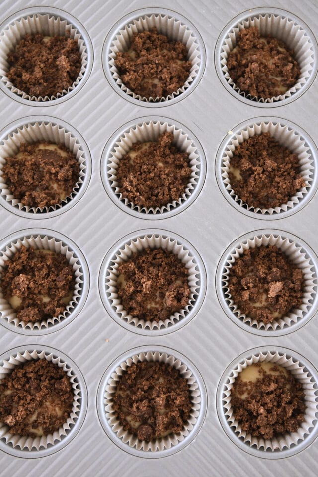Twelve muffins topped with cinnamon crumble in muffin tin.